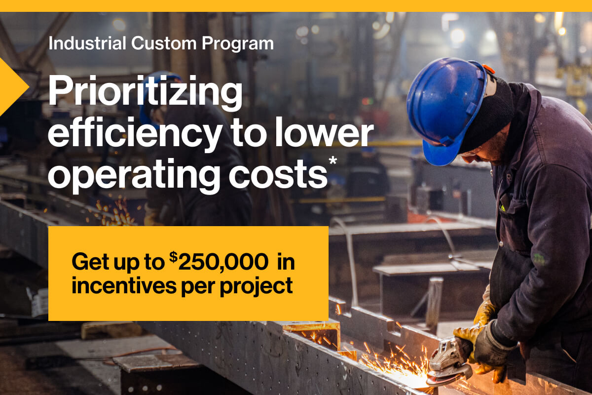 Industrial Custom Program. Prioritizing efficiency to lower operating costs*. Get up to $250,000 in incentives per project: Image of two workers wearing blue helmets while welding steel on a large assembly line. Bright golden sparks fly under the hazy glow of factory lights.