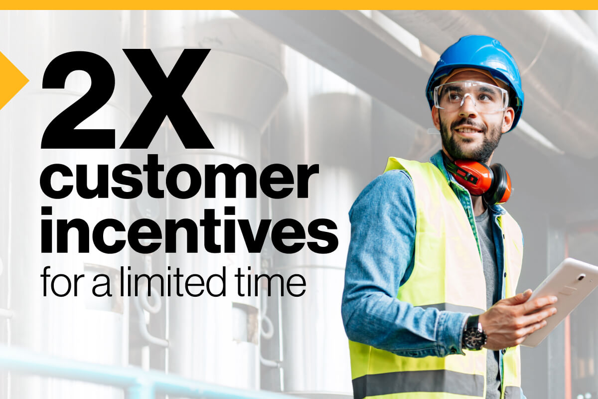2X customer incentives for a limited time: Image of a worker in a hard hat, goggles and vest smiling while holding a tablet device.