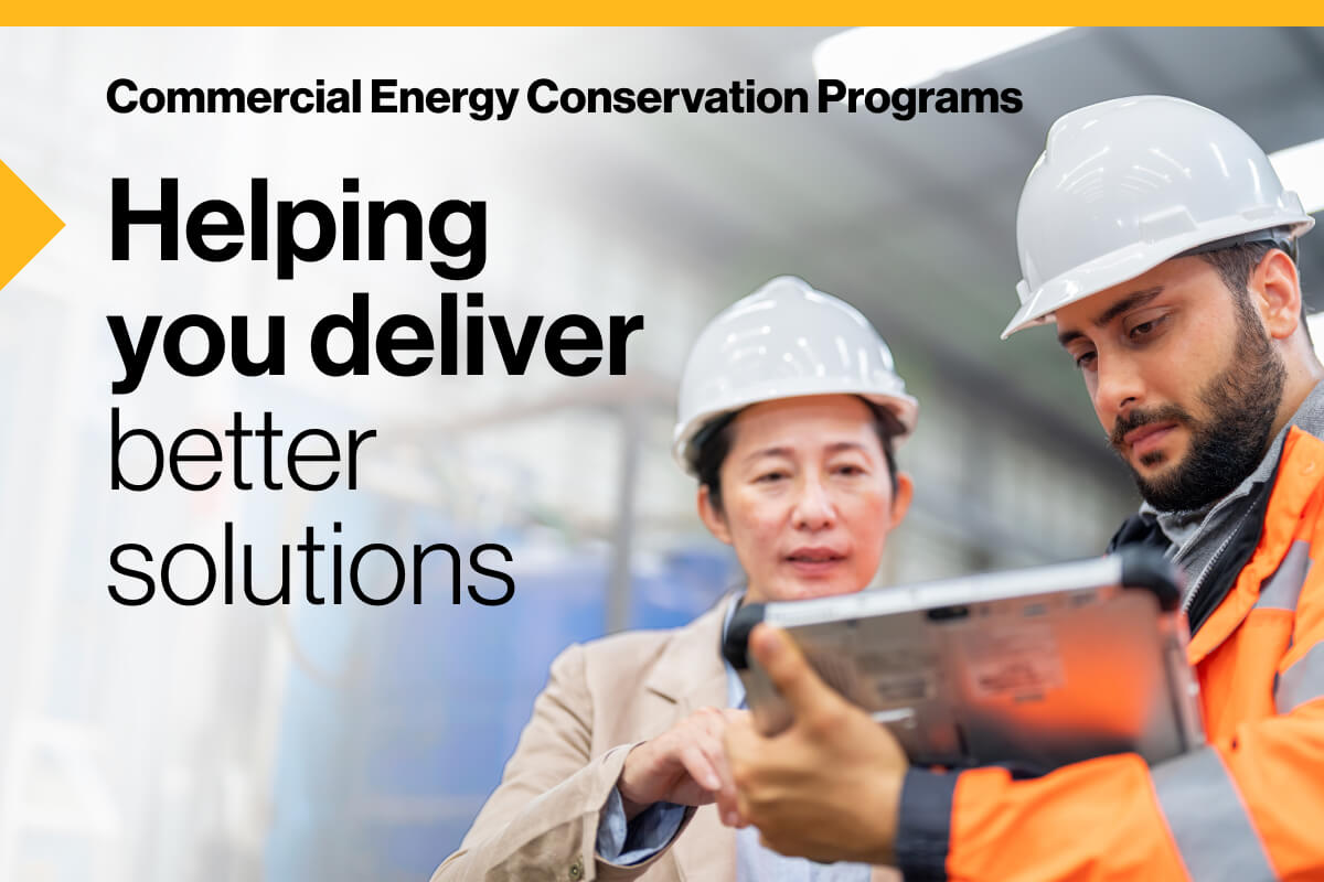 Commercial Energy Conservation Programs. Helping you deliver better solutions: Image of two engineers wearing hard hats and safety gear using a tablet to review information, while standing in an industrial setting.
