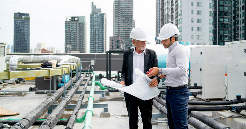 Two technicians talking on a factory rooftop, holding a chart.