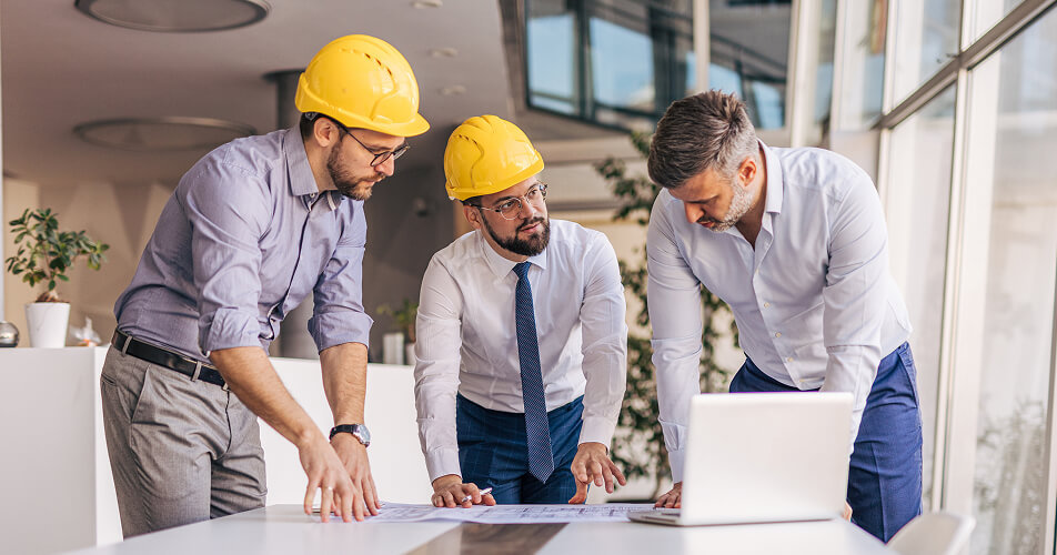 Three technicians talking to each other while looking at a chart on the table.