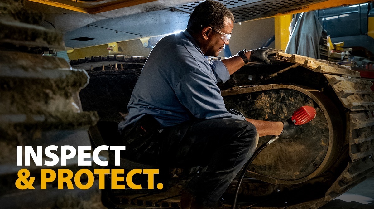 Man performing inspection on equipment treads.