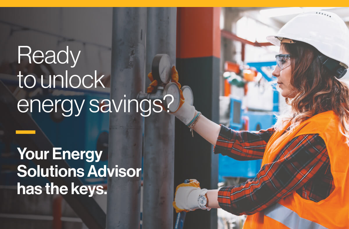 Ready to unlock energy savings? Your Energy Solutions Advisor has the keys: An image of a worker in a hard hat and protective goggles inspecting valves in a factory.